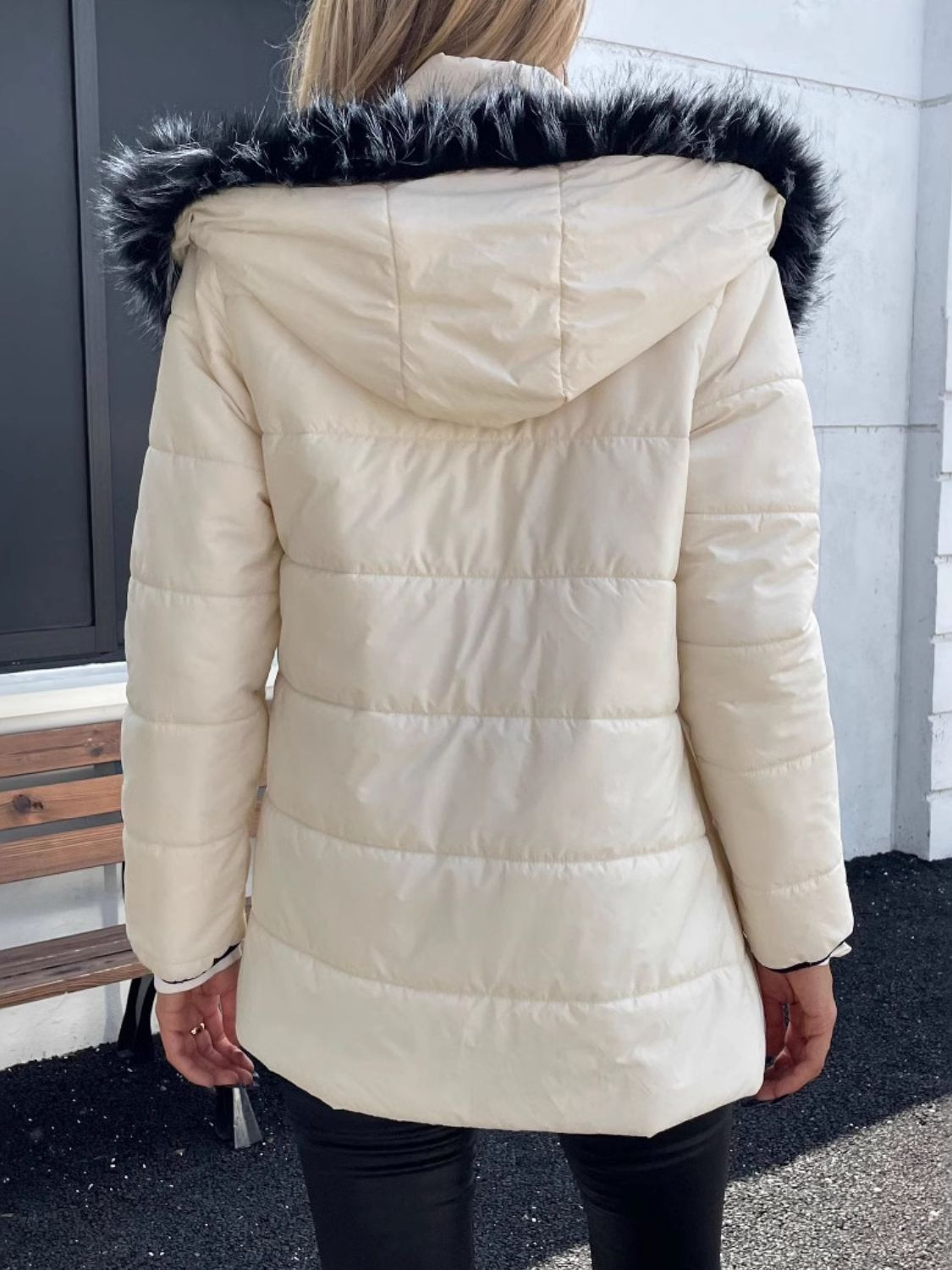 Woman wearing a zip-up long sleeve hooded winter coat with faux fur trim, showcasing the back design in an outdoor setting.