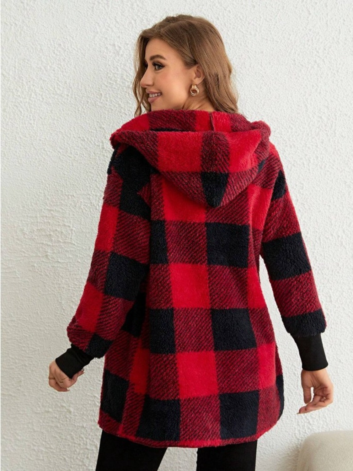 Woman wearing red and black plaid long sleeve hooded coat, showing back details.